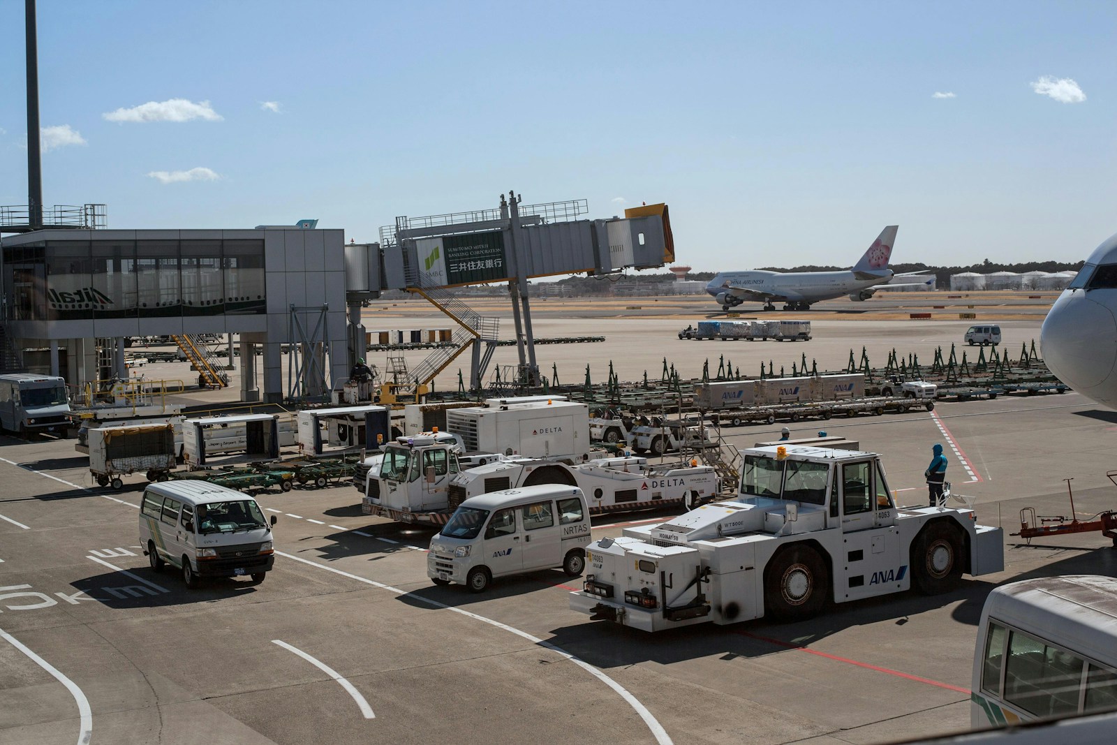 Parking de aeropuerto con coches aparcados y un avión al fondo